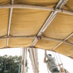 Boat - Side view of anonymous male in casual clothes setting sail on traditional boat floating on river on sunny day