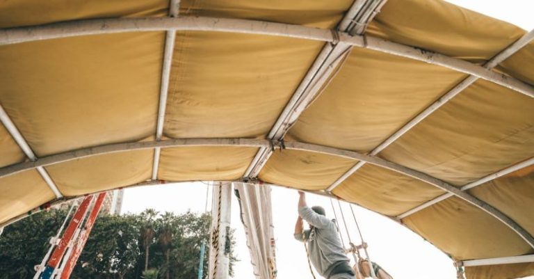 Boat - Side view of anonymous male in casual clothes setting sail on traditional boat floating on river on sunny day
