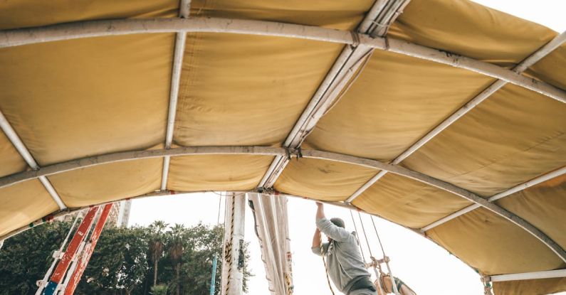 Boat - Side view of anonymous male in casual clothes setting sail on traditional boat floating on river on sunny day