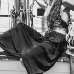 Hull - Black and white full body side view of stylish female in hat sitting on wooden ship during cruise on summer day